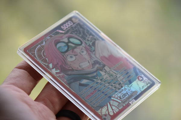 Koby Alt Art PCG 10 in a Slim Player Slab held in hand against blurry background.
