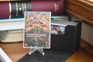 Kyros Alt Art Leader in a PCG 10 Slim Player Slab next to black deckbox.