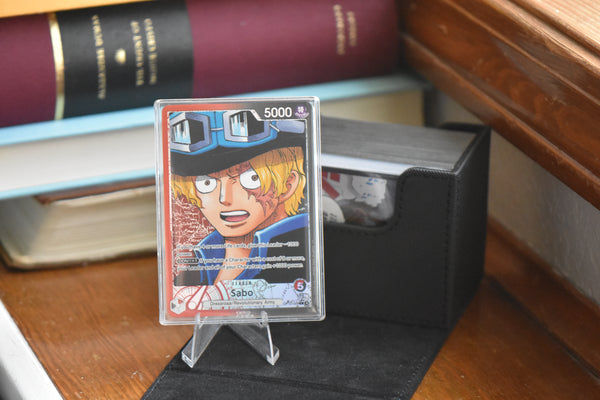 Sabo OP13 Alt Leader in a PCG Slim Player Slab next to a black deckbox - front view.