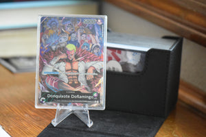 Doflamingo Alt Art PCG 9.5 in a Slim Player Slab next to black Sidewinder deckbox.